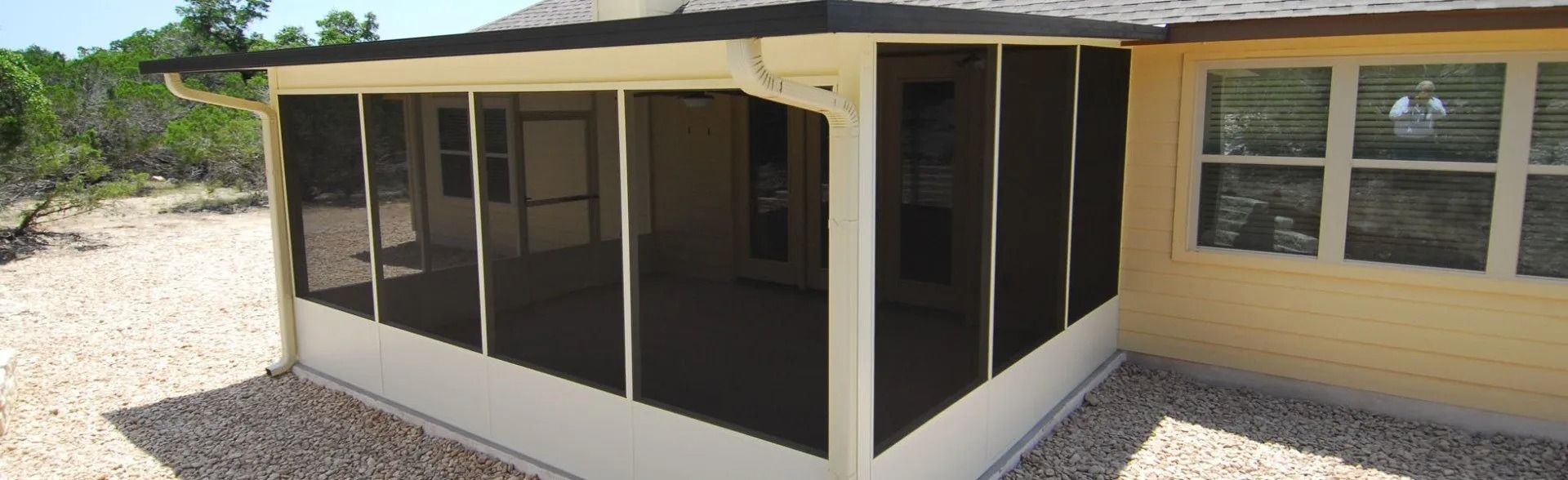 A screened in porch on the side of a house.