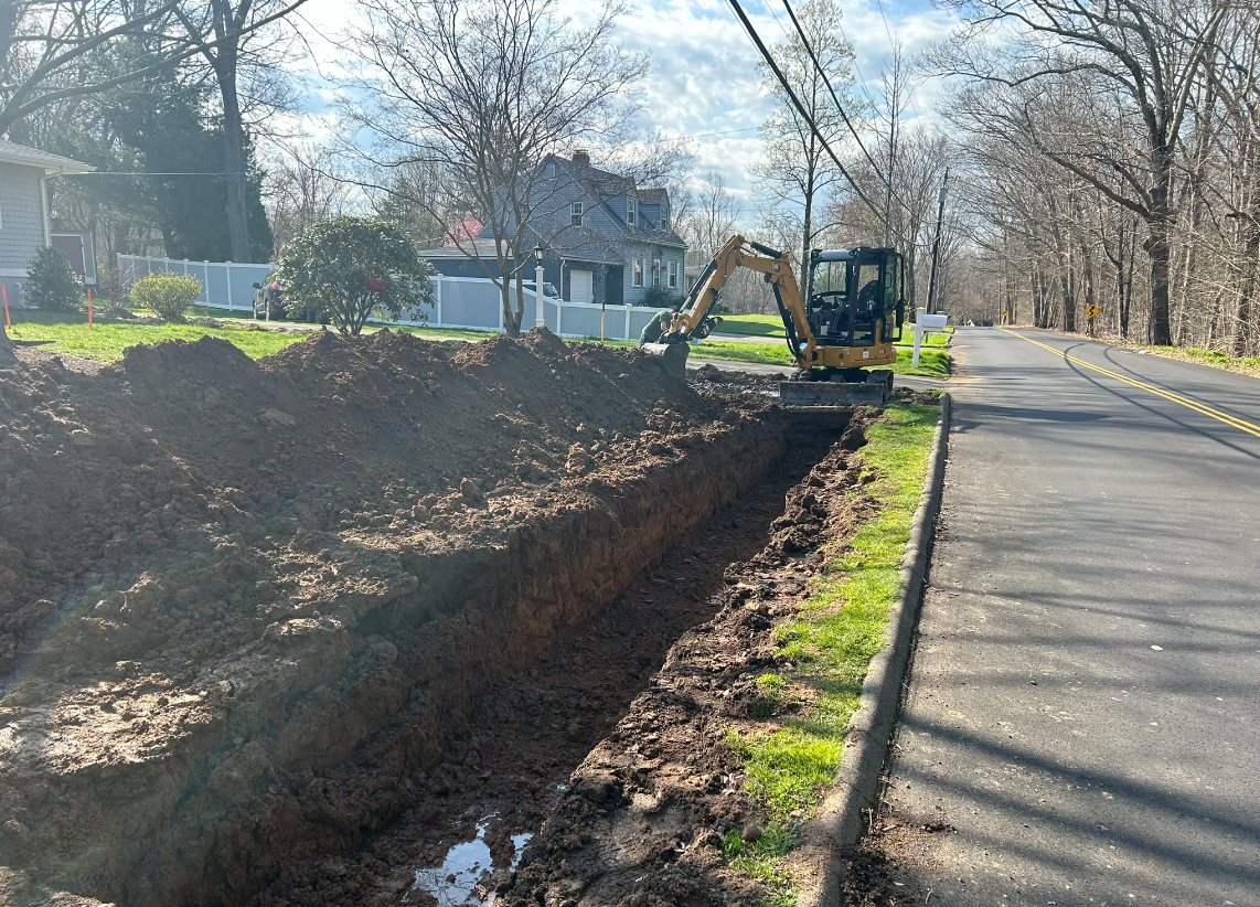 An excavator is digging a hole in the side of a road.