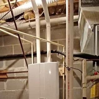 Water heater and pipes in a basement with cinder block walls.
