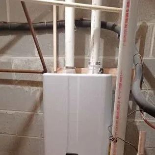 White water heater mounted on a concrete wall with pipes running to it
