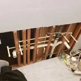 Exposed plumbing pipes inside a wall, showing the water supply and drain lines.