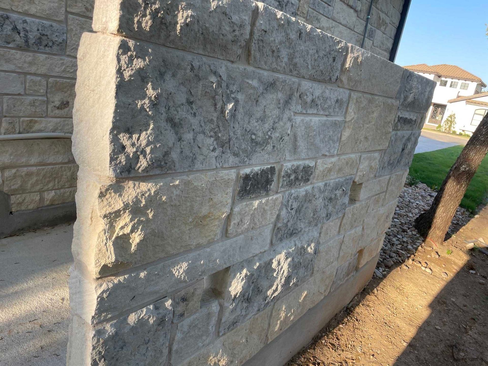 Stone brick wall on a building's exterior. The stones are light grey and beige.