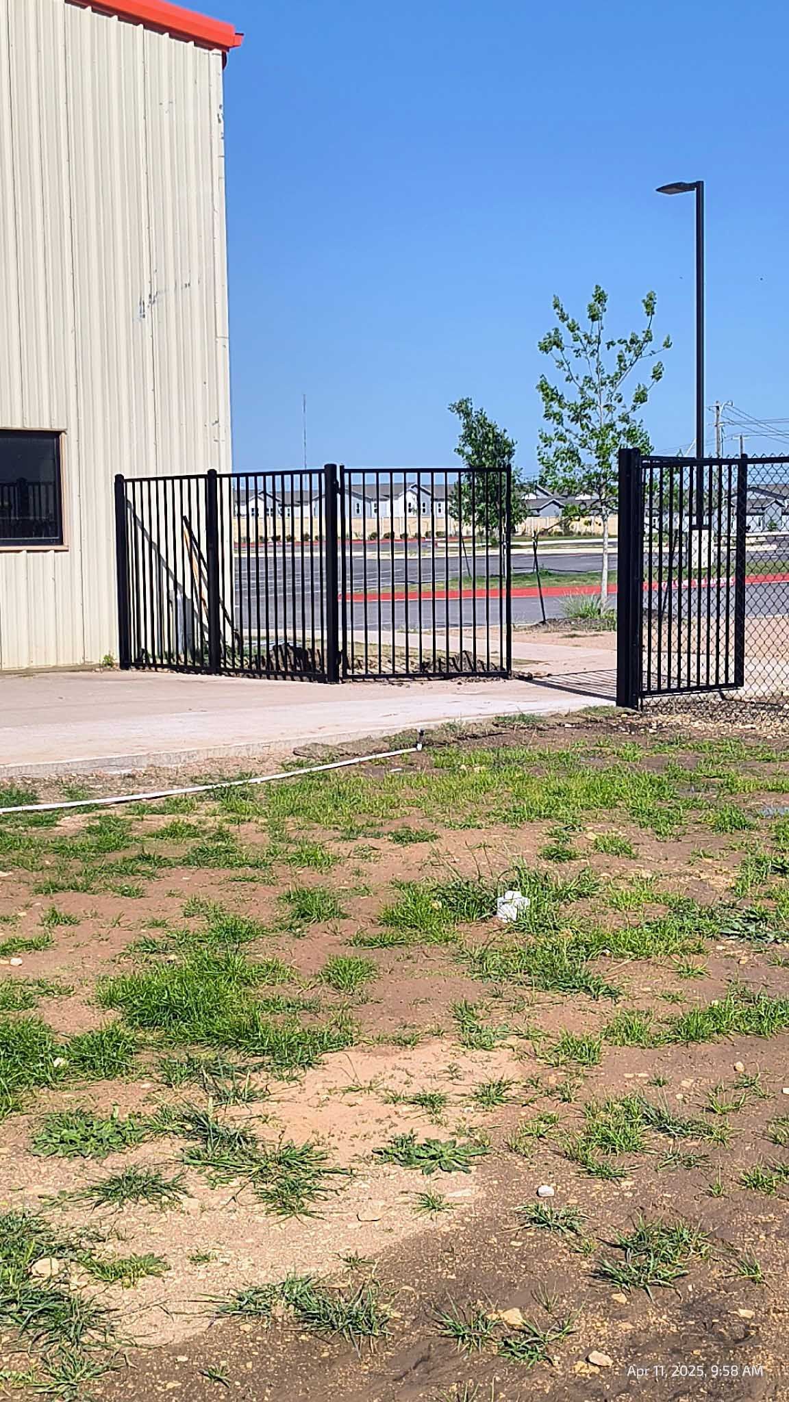 Black metal fence gates in front of a building, clear blue sky overhead.