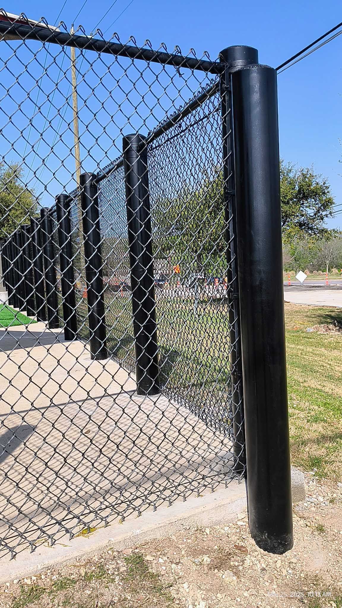 Black chain-link fence with black posts. Sunny outdoor setting.