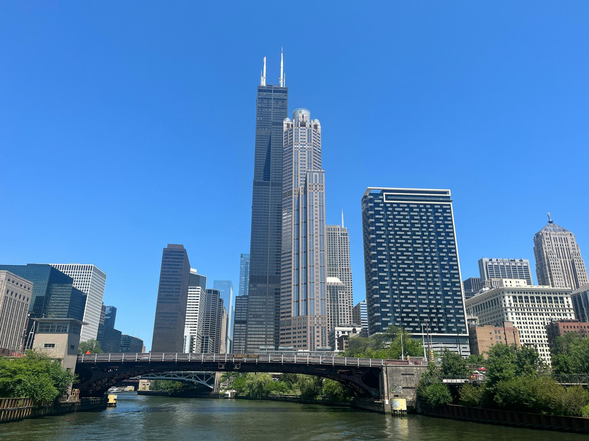 Chicago skyline with Willis Tower over the Chicago River and a bridge. Sunny day, clear blue sky.