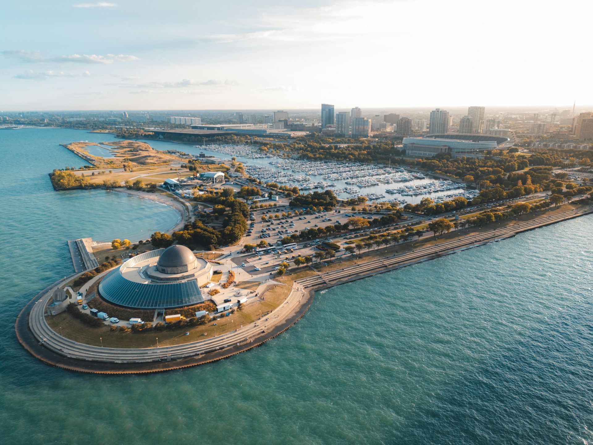 Aerial view of Chicago's lakefront, featuring Adler Planetarium, harbor with boats, and city skyline.