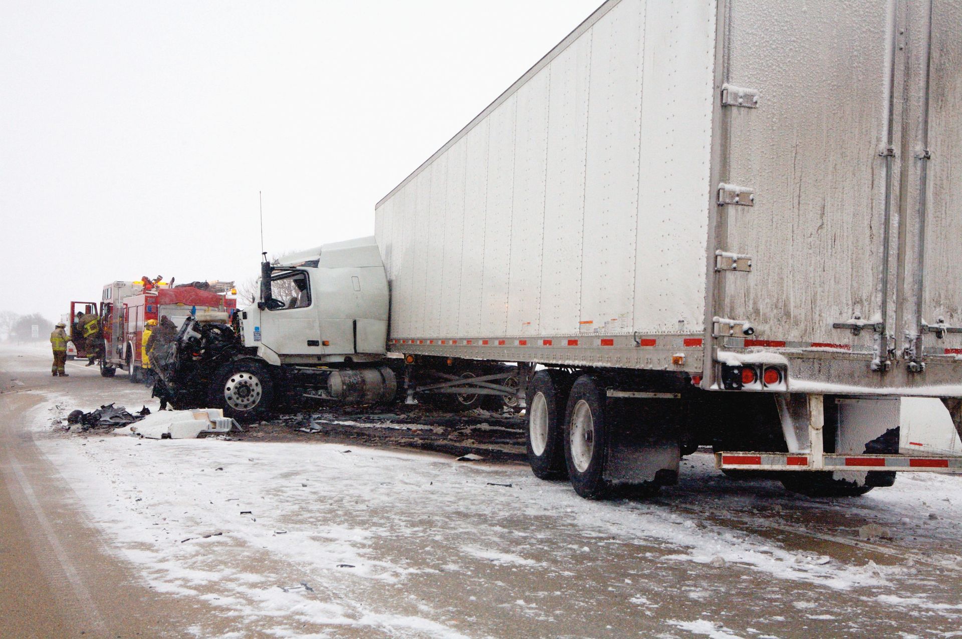 A red car is stuck under a white truck