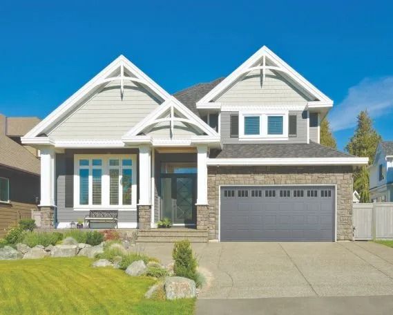 Modern suburban house with gray siding, white trim, and a two-car garage under a blue sky