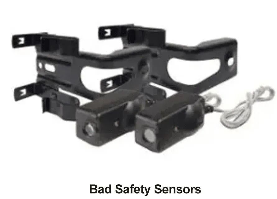 Black metal safety sensor mount with cable, labeled “Bad Safety Sensors”