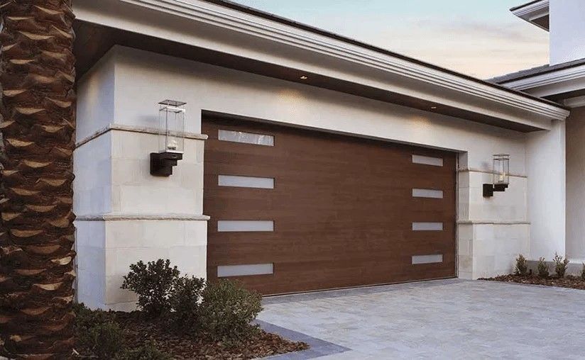 Modern house garage with a brown door and white trim, flanked by wall-mounted lanterns.