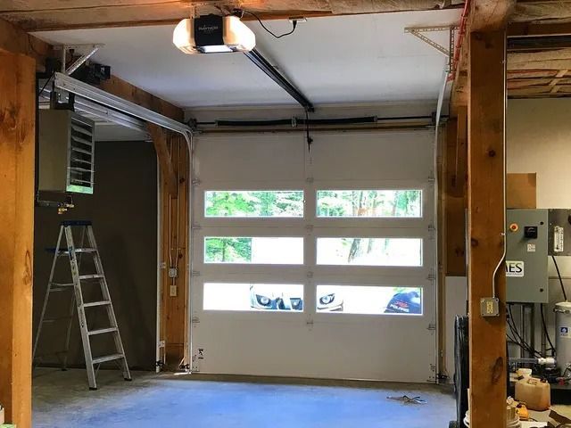 Garage interior with open door, ladder, ceiling light, and electrical panel on the right
