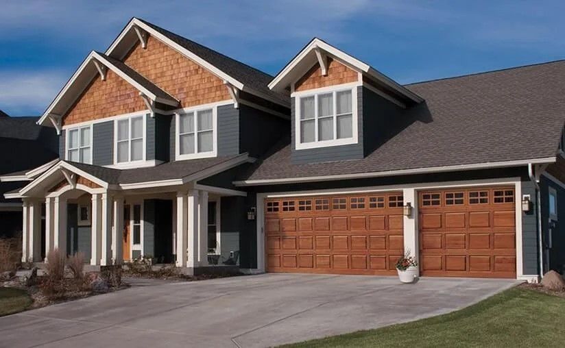 Suburban two-story house with a brick facade, three-car garage, and a paved driveway under a blue sky