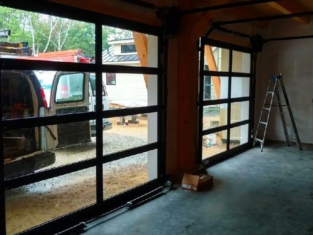 Garage interior under construction with open framed window bays, ladder, and parked truck outside.