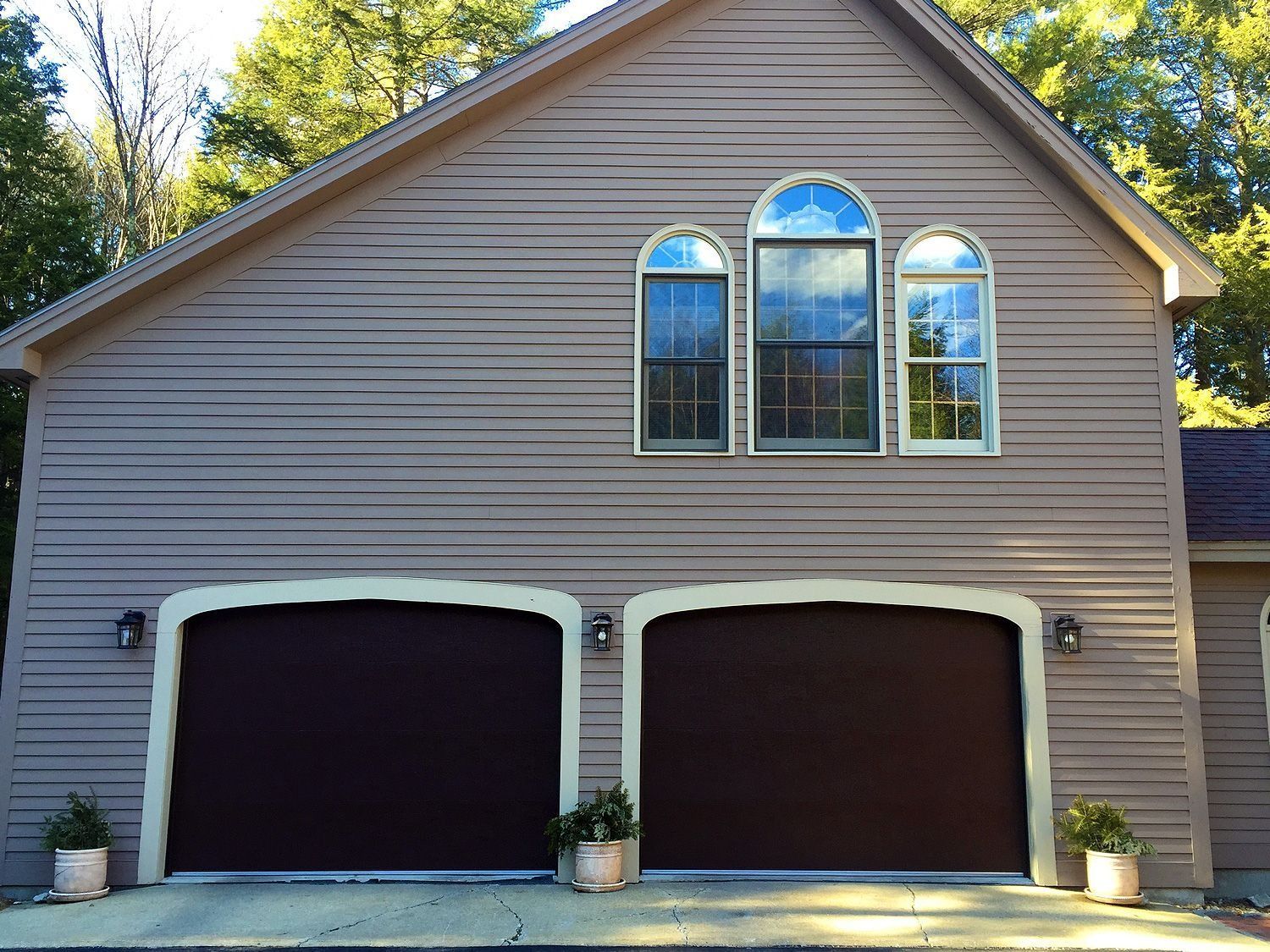 Two-car gray garage with white-trimmed arched windows and a peaked roof.