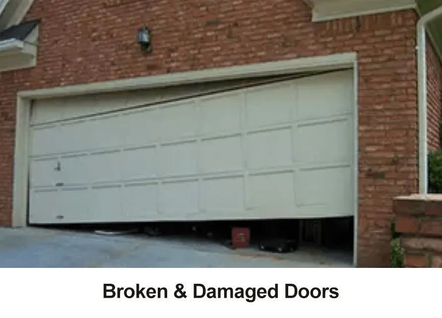 Damaged white garage door hanging open on a brick house