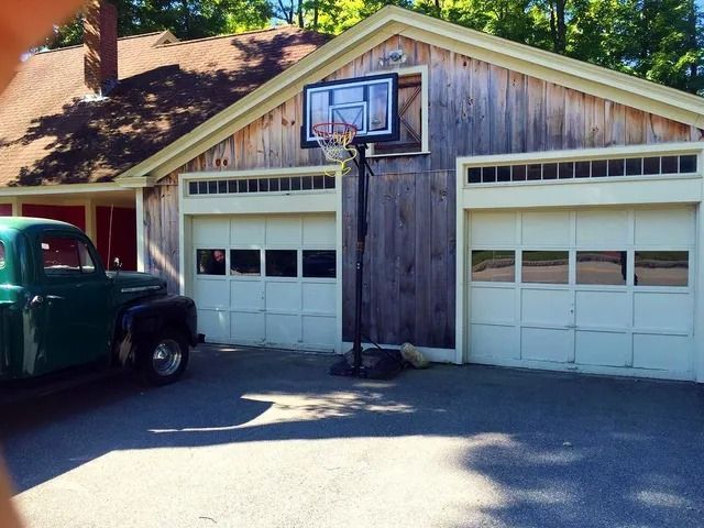 Two-car garage with a basketball hoop above the center door and a green truck parked on the left