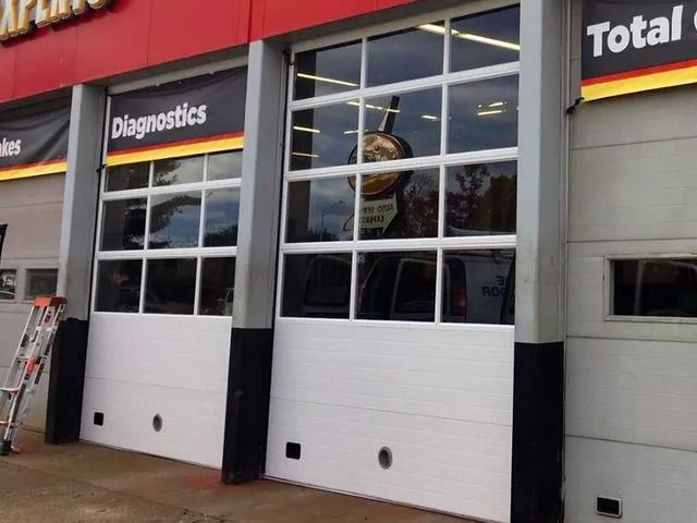Auto service storefront with white garage doors and signs for Diagnostics and Total