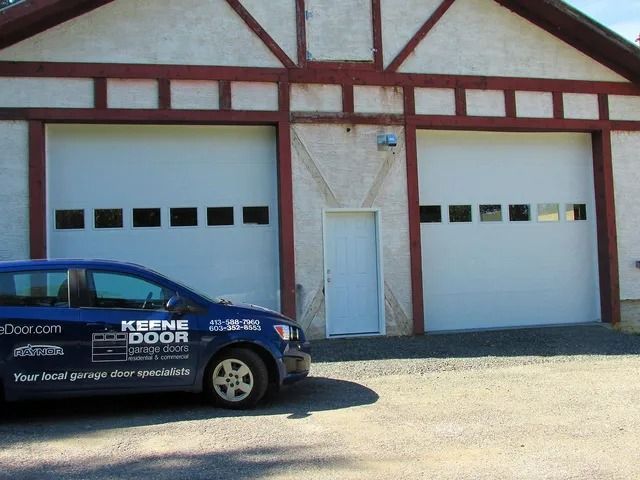 Blue service van parked in front of two white garage doors on a red-trimmed building