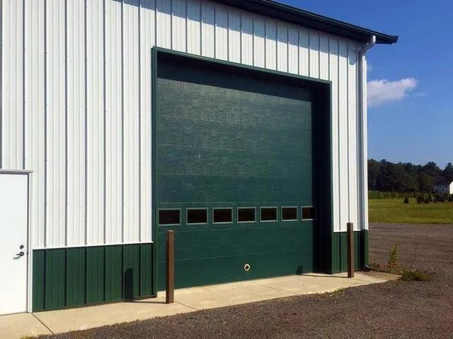 Industrial building with a large green garage door and white metal siding