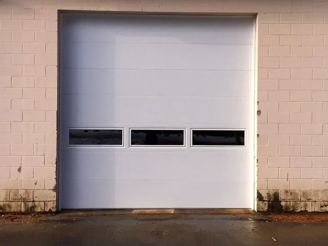 Closed white garage door set in a beige brick wall with three narrow windows.