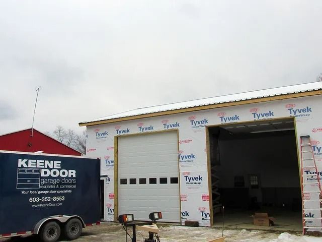 Keene Door Company truck beside a Tyvek-wrapped garage with open bay doors