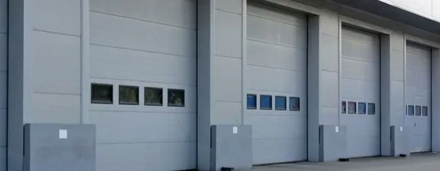 Modern gray industrial warehouse doors with small windows and concrete loading bays