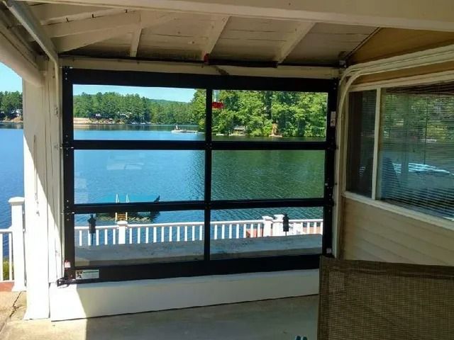 Covered porch overlooking a lake, with screened windows and a white railing at the water’s edge