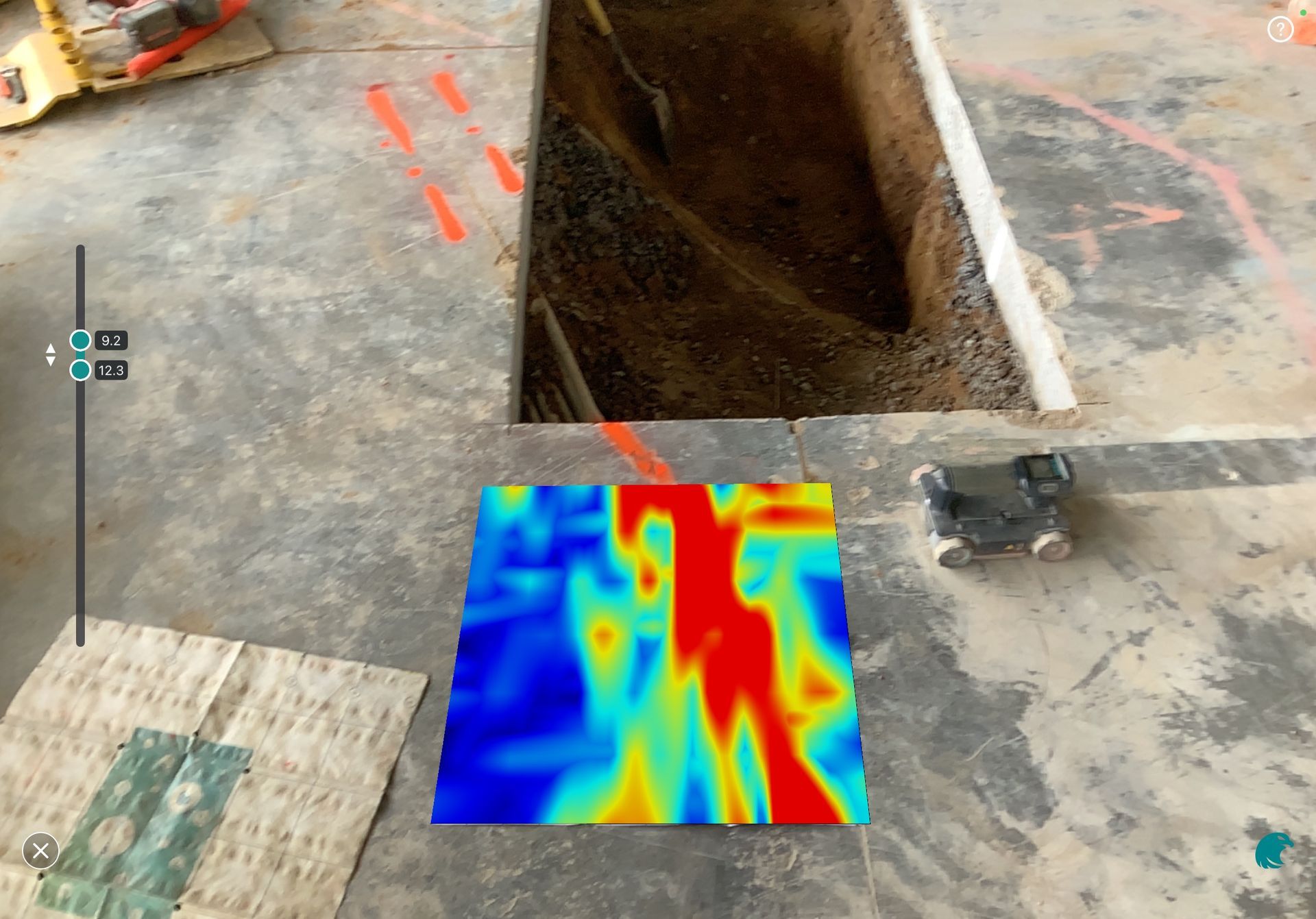 Construction site floor with a pit and a colorful thermal heatmap overlay near the center