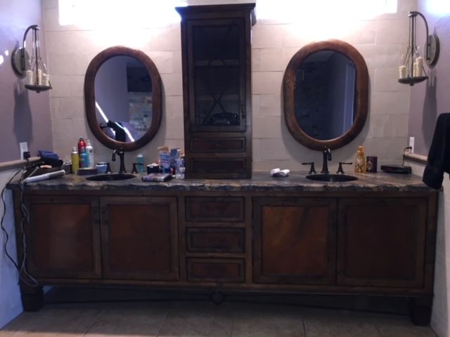 A bathroom vanity with two sinks, cabinets, and mirrors