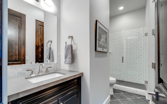 a bathroom with a sink, mirror, cabinets, toilet, and walk in shower