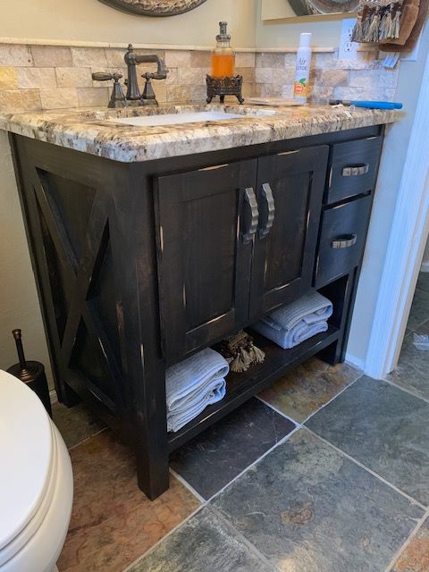 A bathroom with a sink, cabinets, and vanity