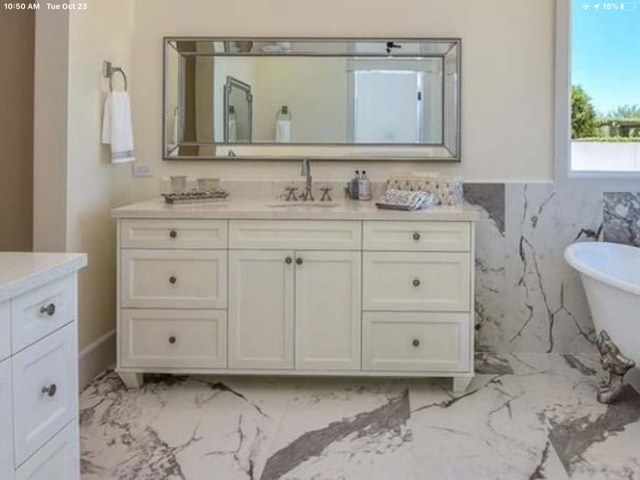 A bathroom with a sink, cabinets, mirror, and bathtub