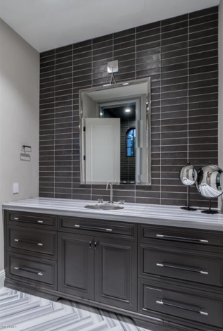 A bathroom with a large sink, cabinets, and a mirror