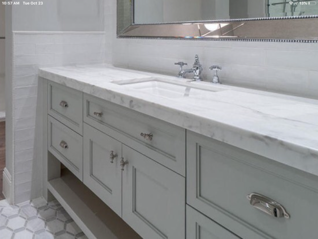 A bathroom with two sinks, gray cabinets, and a mirror