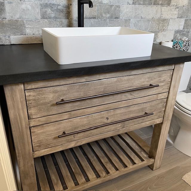 A bathroom vanity with cabinets and a sink next to a toilet