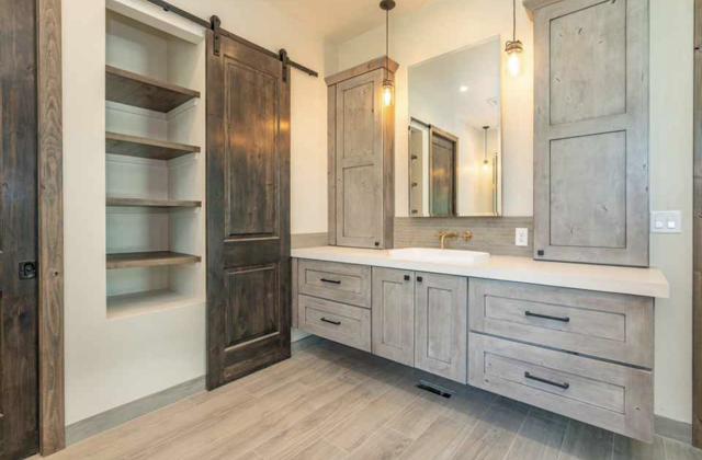 A bathroom with a sliding barn door, a sink, and wooden cabinets
