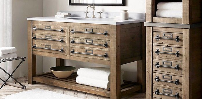 A bathroom with a wooden vanity, cabinets, and mirror