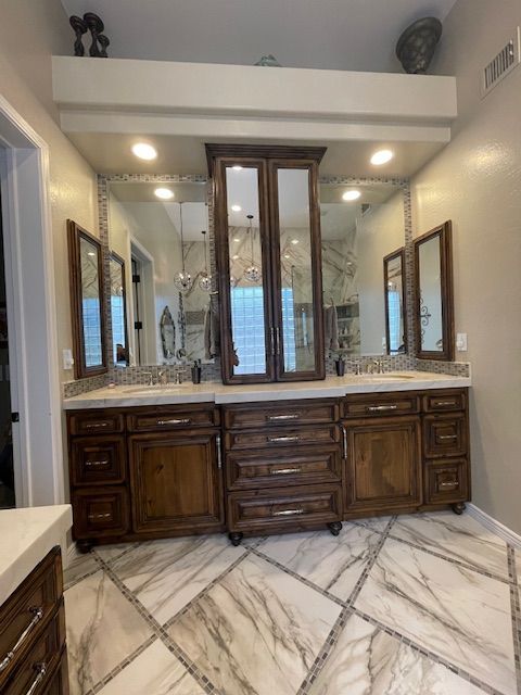 A bathroom with two sinks, two mirrors, and wooden cabinets
