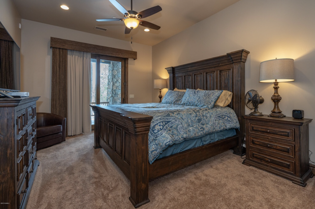 A bedroom with a king size bed, nightstand, dresser, and ceiling fan
