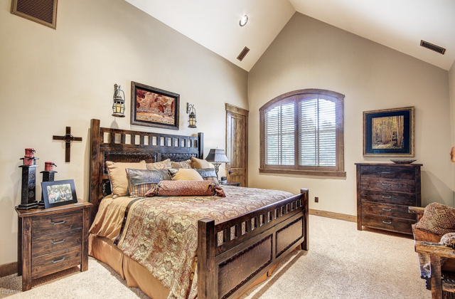 A bedroom with a king size bed, two nightstands, a dresser, and a window