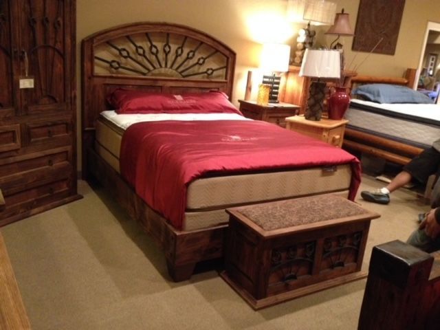 A bed with a red comforter and a wooden headboard