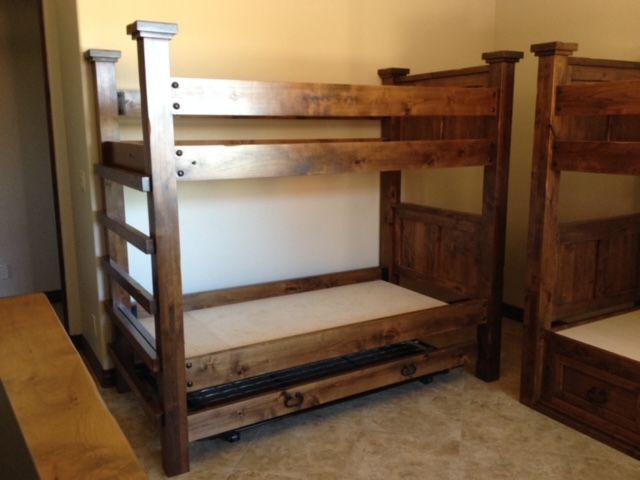 A wooden bunk bed in a room with two other bunk beds