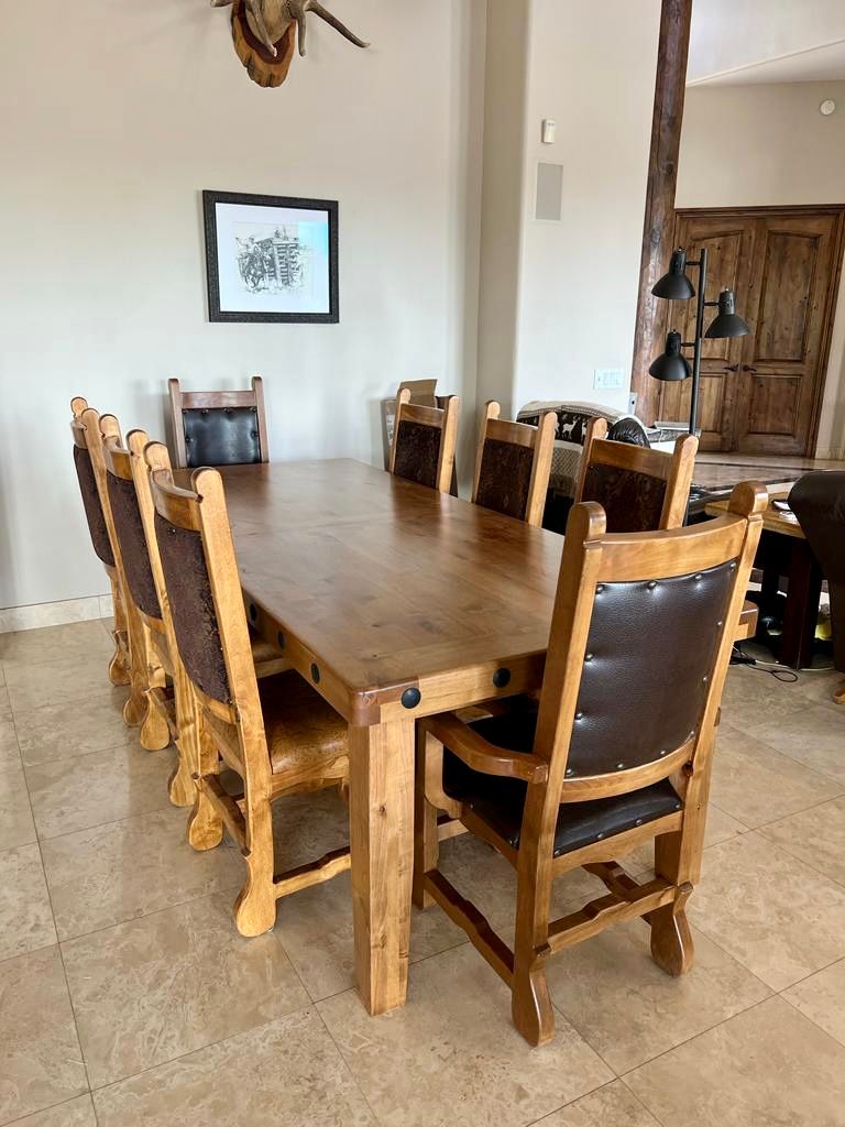 A dining room with a wooden table and chairs and a picture on the wall