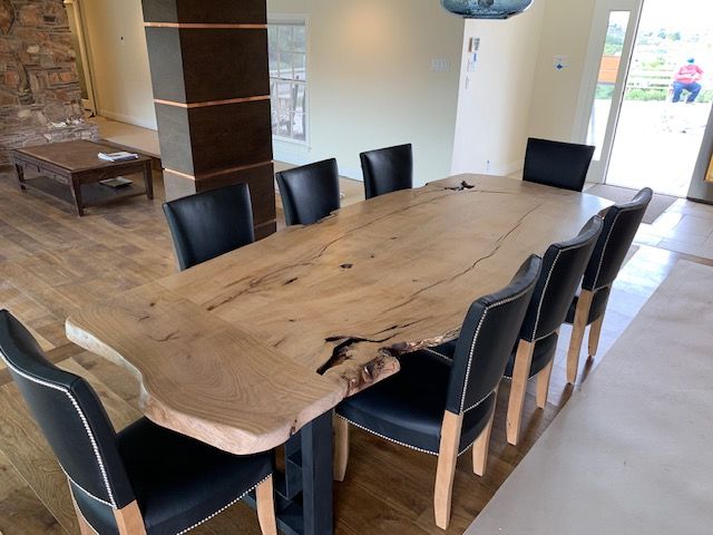 A long wooden table with black chairs in a dining room