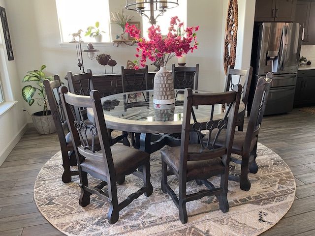A dining room table and chairs with a vase of flowers on top of it