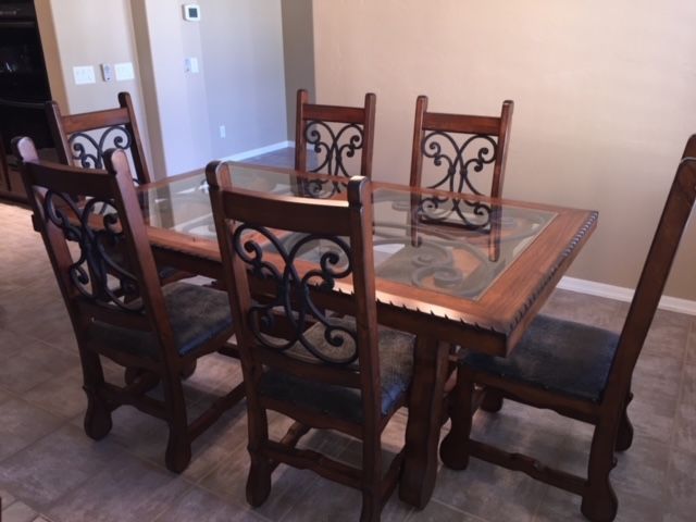 A dining room table with four chairs and a glass top