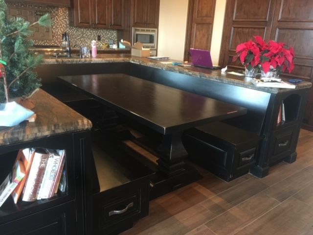 A kitchen with a dining table and benches in it