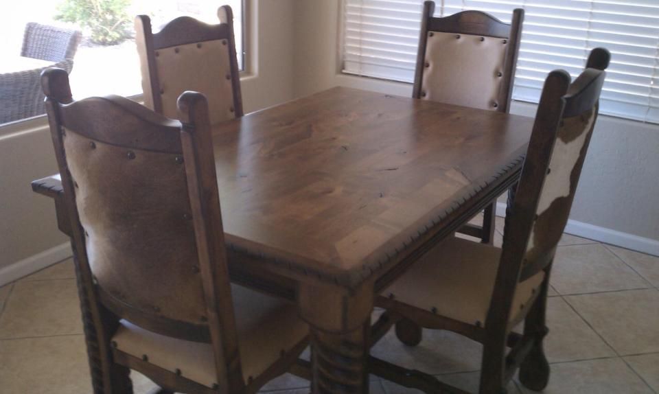 A wooden dining table with four chairs in front of a window