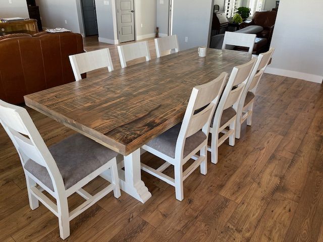 A wooden dining table with white chairs in a living room