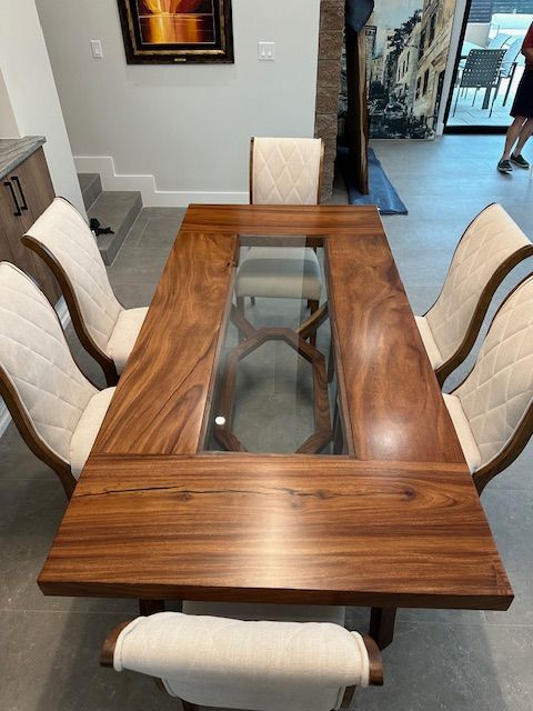 A wooden dining table with a glass top and four chairs